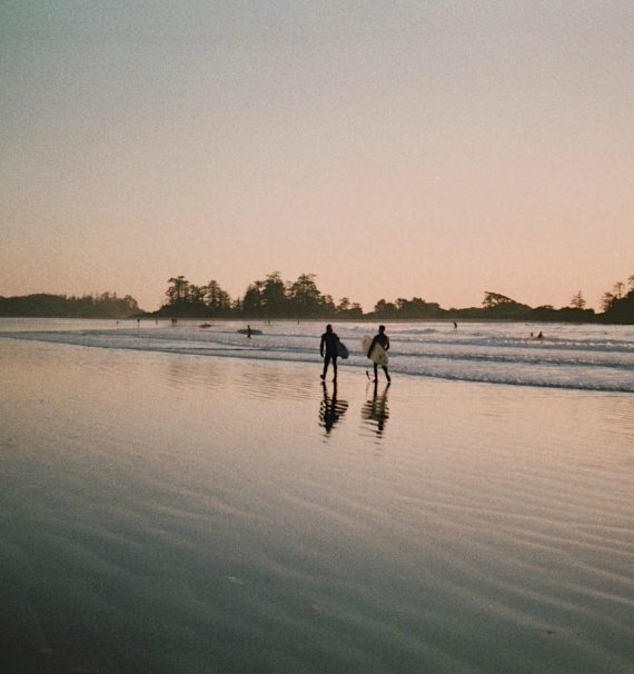 Two people walking on a beach at sunset